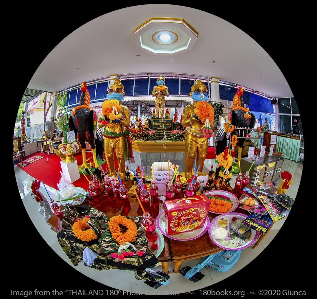 image of Offerings and images of Ai Daeng (Red Boy) and Ai Dum (Black Boy). Ai Khai Kotr Ruay stands alone on a higher pedestal behind them.
